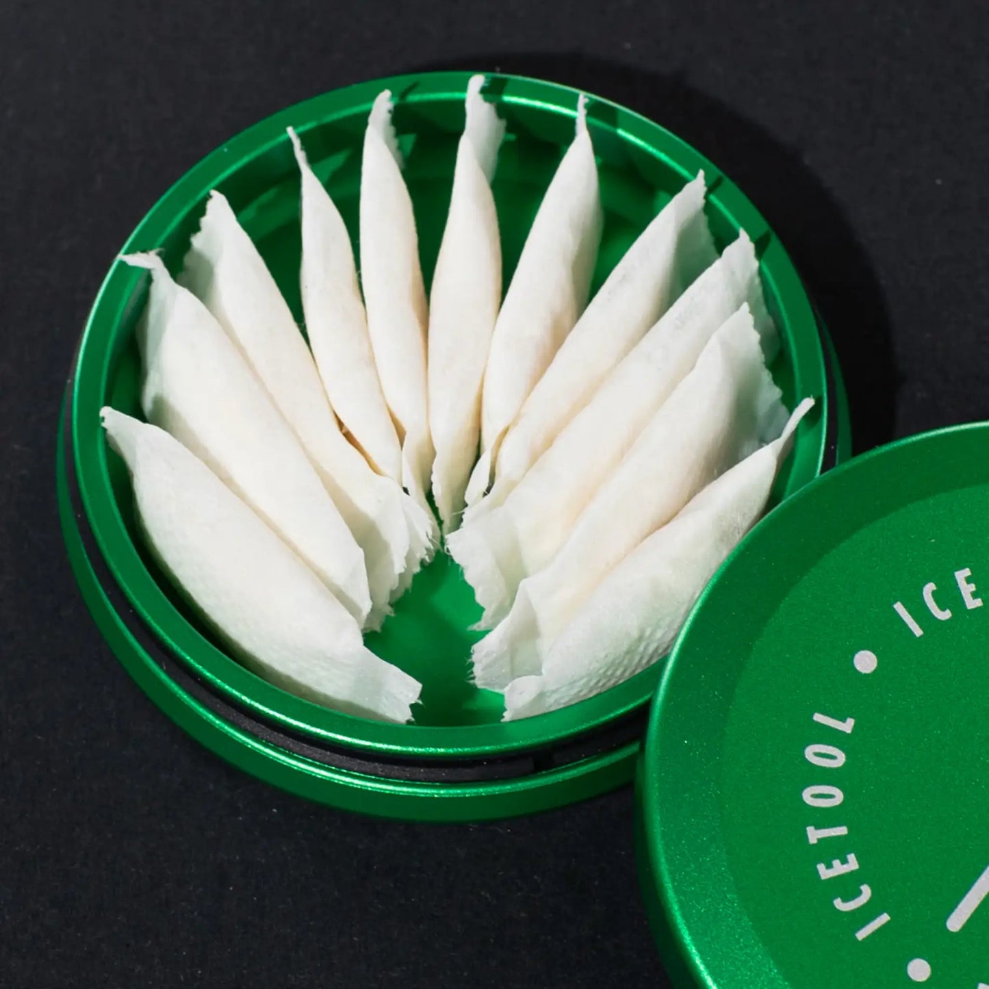 Close up of the inside of a green container full of nicotine pouches on a dark grey background.