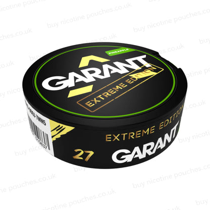 Angled shot of a black nicotine pouch container with green, white and gold 'GARANT EXTREME EDITION PINEAPPLE' branding on a white background.
