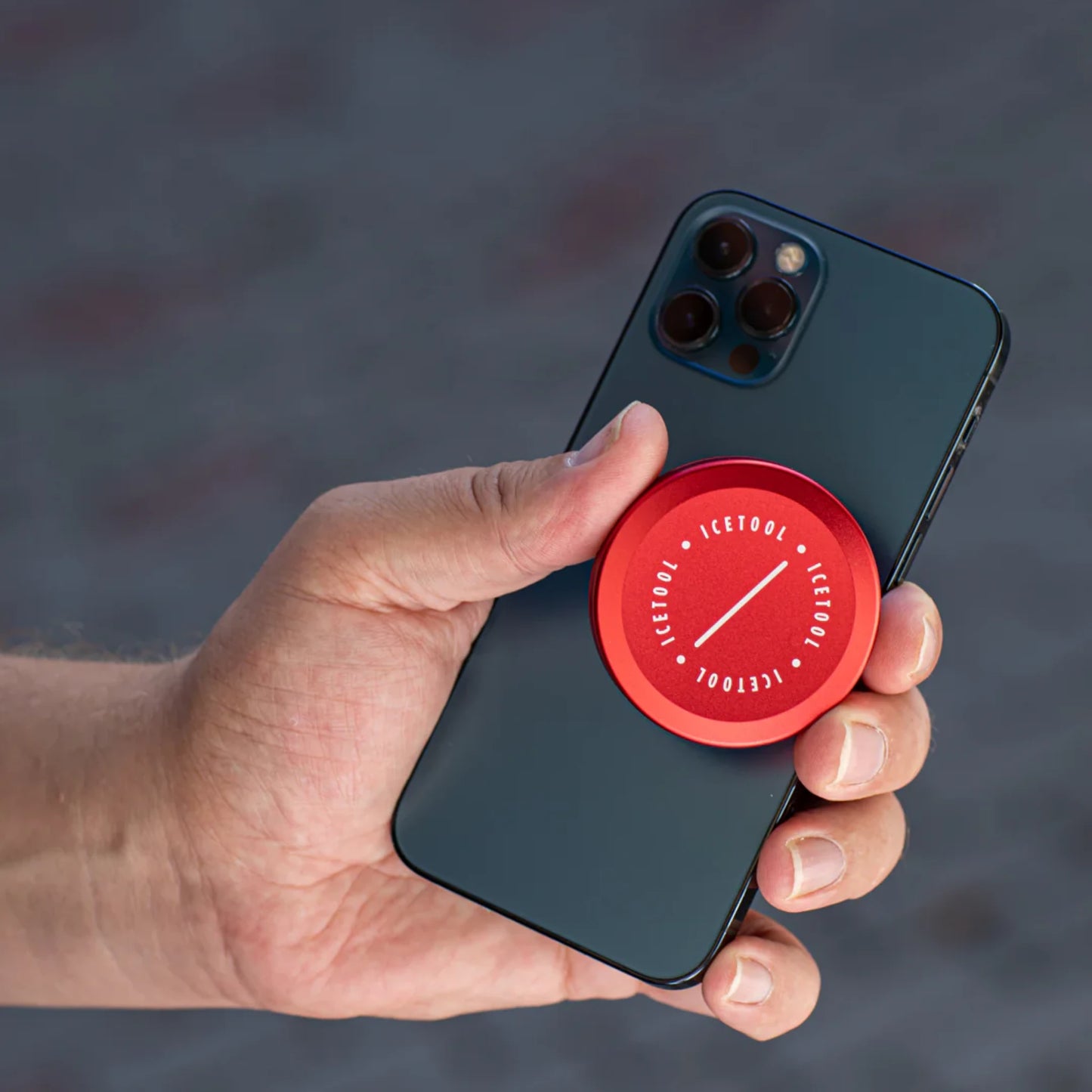 Hand holding a black smartphone and a red circular container with Icetool branding.