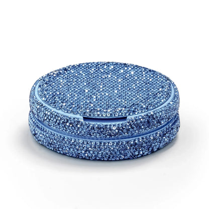 Angled shot of a circular container covered in blue rhinestones on a white background.