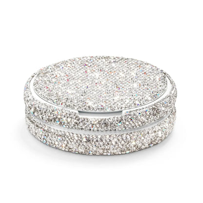 Angled shot of a circular container covered in silver rhinestones on a white background.